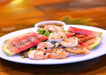 Johnny Longboats Grilled Shrimp & Watermelon served on a round plate.